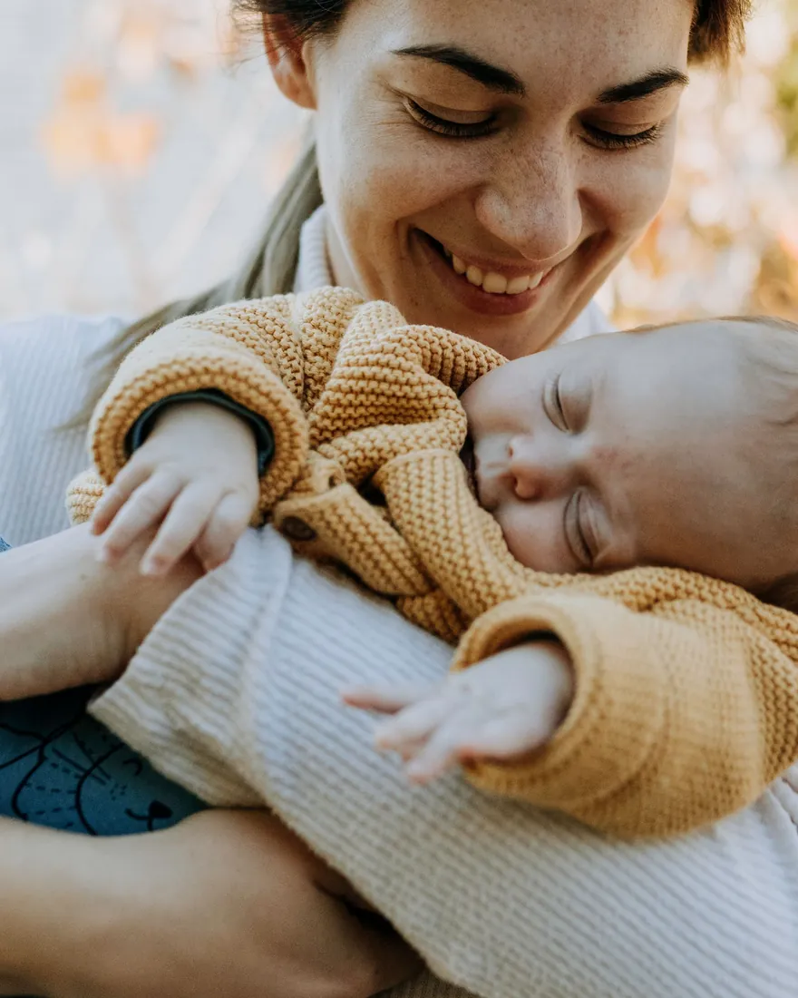 Mãe segurando um recém-nascido no colo, ao ar livre